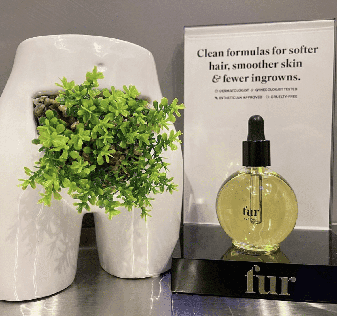 Luxurious Fur Oil displayed next to a modern plant pot and an informational sign.